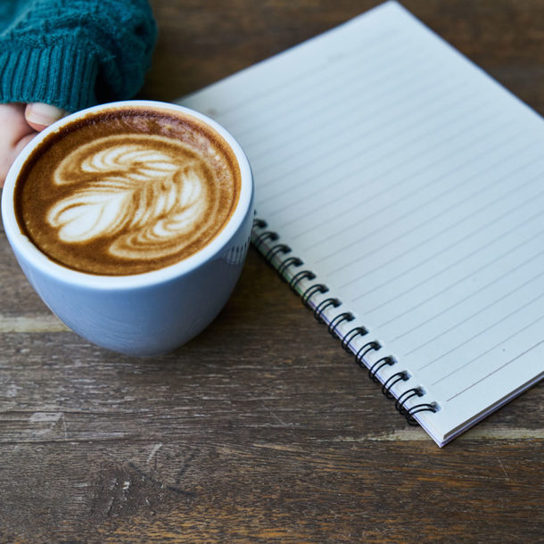 digital marketing agency hand holding cup of coffee and notepad on the table