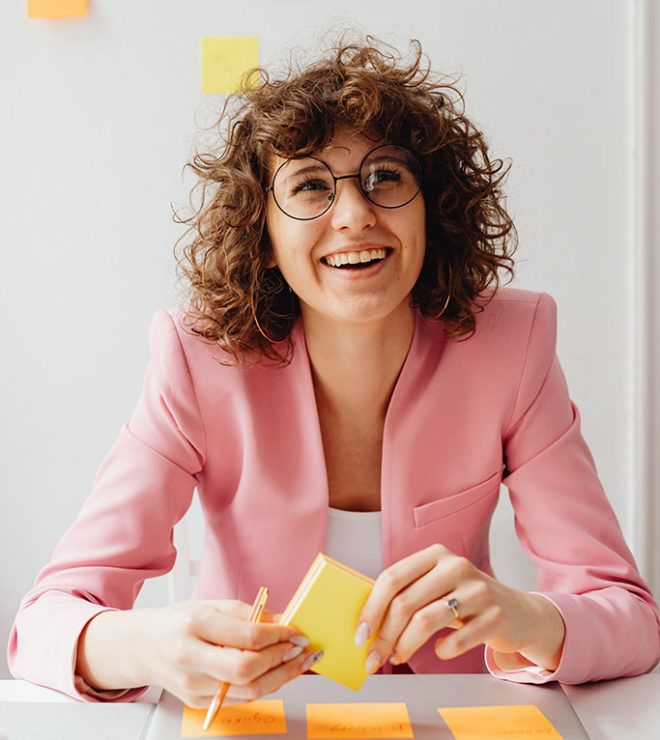 internet marketing agency for attorneys woman in pink jacket and glasses with stickers on the wall and smiling